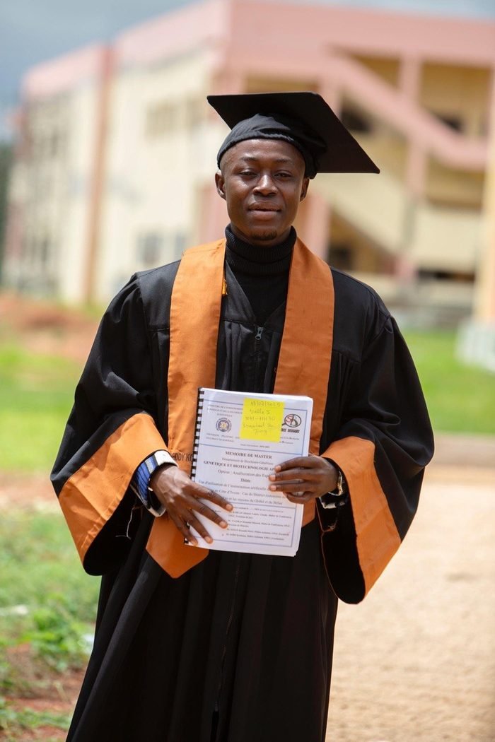 Freddy Konan en toge de diplômé, tenant son mémoire de master en génétique et biotechnologie appliquée